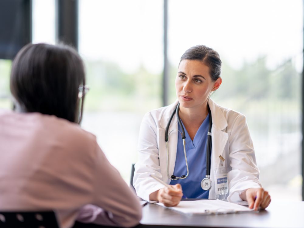 Atendimento de cliente em consultório médico com discussão sobre carência em plano de saúde empresarial. Veja tudo sobre carência plano de saúde empresarial.